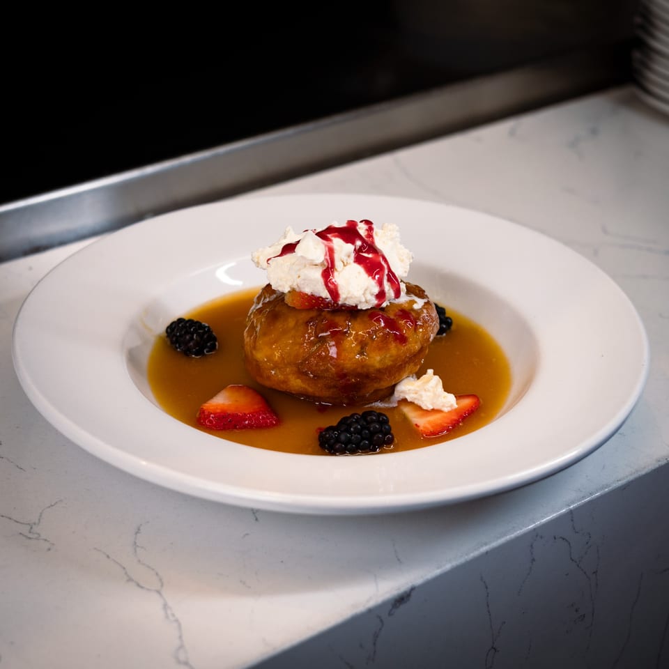 Cucina Colore's Italian dessert: a golden cake with whipped cream, berry drizzle, strawberries, and blackberries.